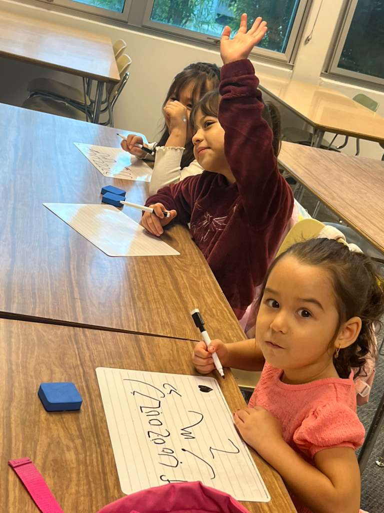 Young students raising hands during a Knowledgeseekers class