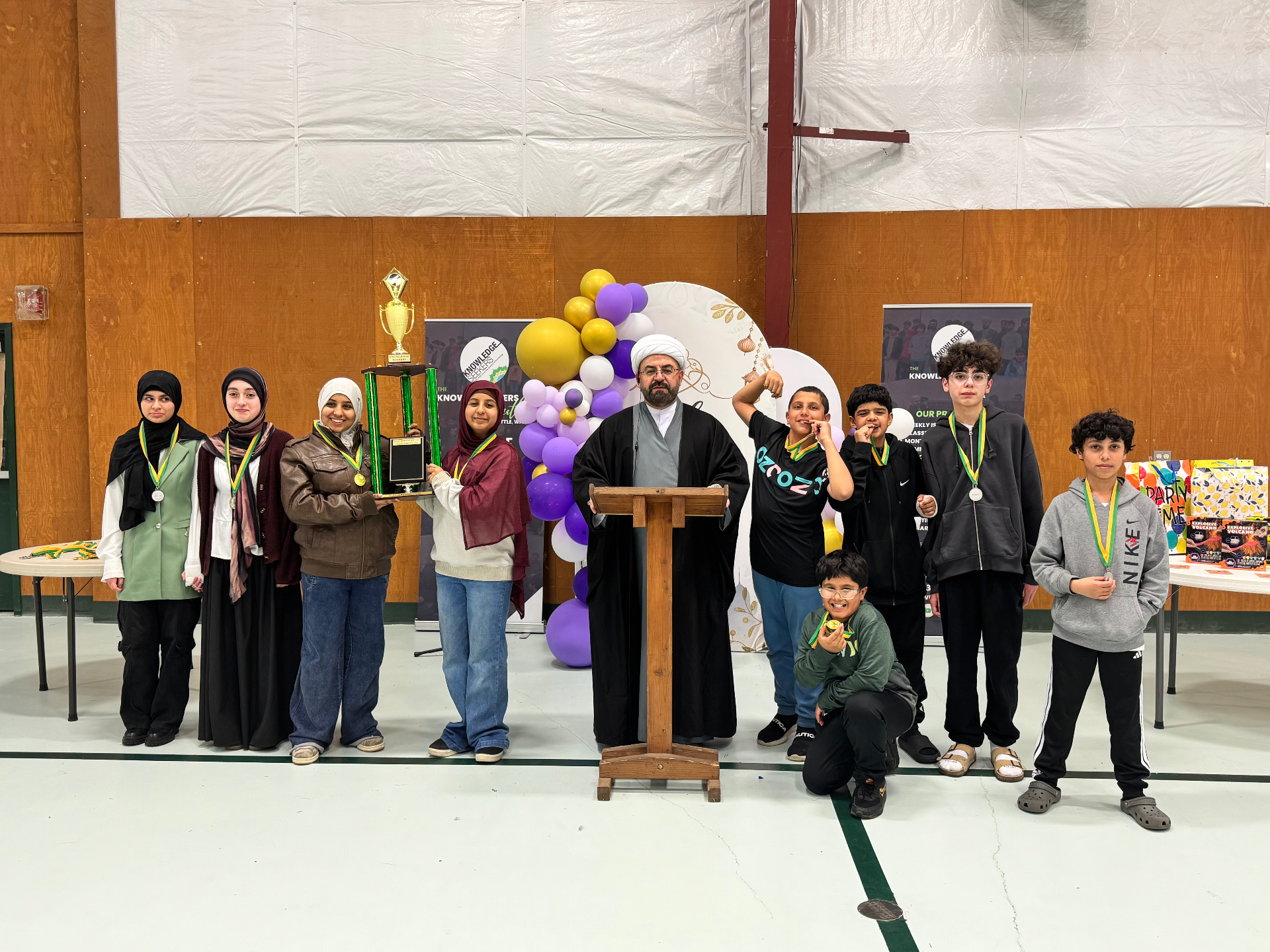 Youth receiving awards and trophy at a Knowledgeseekers ceremony